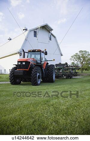 Stock Image - USA, Illinois, Metamora, Tractor by barn on farm. Fotosearch