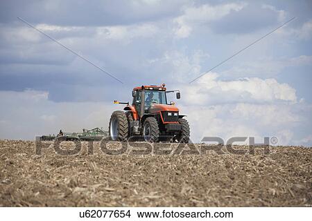 Picture - USA, Illinois, Metamora, tractor plowing field. Fotosearch