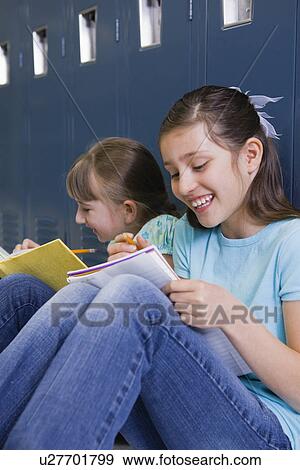USA, Illinois, Metamora, Two girls (8-9) sitting at lockers in school corridor and doing homework View Large Photo Image Stock Photo - USA, Illinois, Metamora, Two girls (8-9) sitting at lockers in school corridor and doing homework. Fotosearch