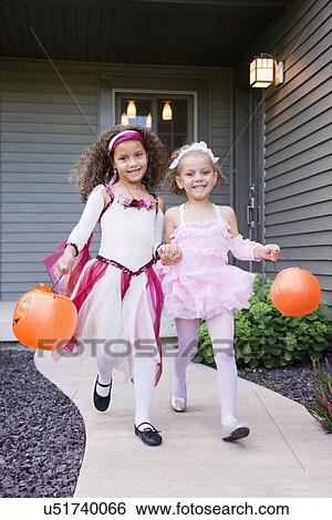 Stock Photograph - USA, Illinois, Metamora, Two girls (6-7, 8-9) in Halloween costume walking. Fotosearch