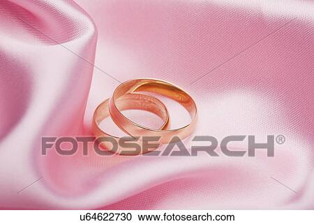 Stock Image - USA, Illinois, Metamora, Two wedding bands on pink silk. Fotosearch