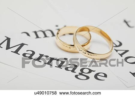 Stock Photo - USA, Illinois, Metamora, Two wedding rings on paper with words connected with wedding. Fotosearch