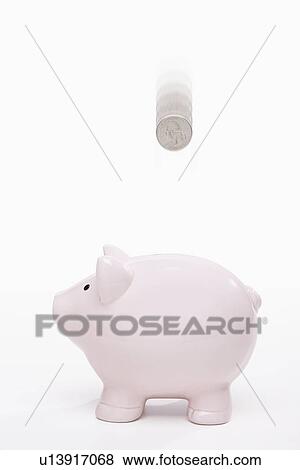 Stock Photo - USA, Illinois, Metamora, US coin falling into piggy bank. Fotosearch