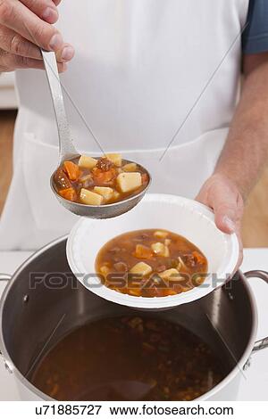 Stock Photo - USA, Illinois, Metamora, Volunteer serving soup. Fotosearch