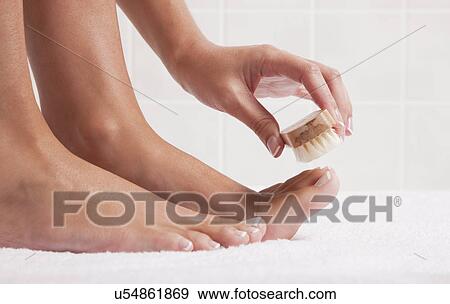 Stock Photo - USA, Illinois, Metamora, woman cleaning foot nails with nail brush. Fotosearch