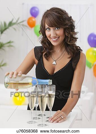 USA, Illinois, Metamora, Woman pouring champagne into flutes at party View Large Photo Image Stock Photo - USA, Illinois, Metamora, Woman pouring champagne into flutes at party. Fotosearch