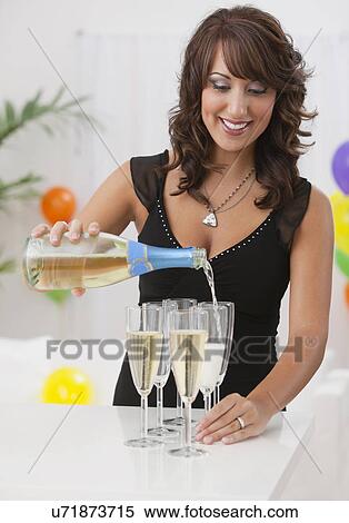 Stock Photography - USA, Illinois, Metamora, Woman pouring champagne into flutes at party. Fotosearch