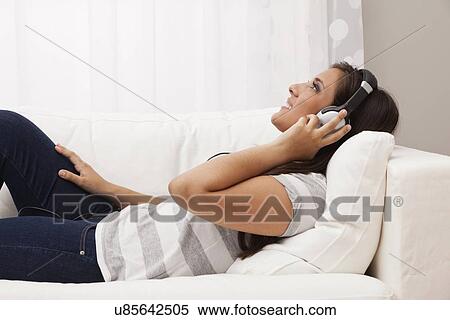 USA, Illinois, Metamora, Woman relaxing on sofa and listening to music View Large Photo Image Stock Photography - USA, Illinois, Metamora, Woman relaxing on sofa and listening to music. Fotosearch
