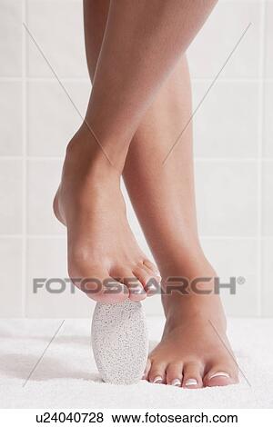 Stock Photo - USA, Illinois, Metamora, woman standing with pumice stone under foot. Fotosearch
