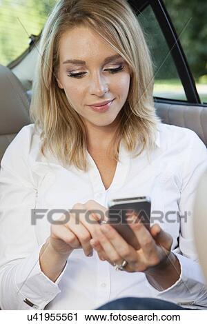 Stock Image - USA, Illinois, Metamora, woman text-messaging in car. Fotosearch