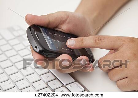 Picture - USA, Illinois, Metamora, Woman texting on his mobile in office. Fotosearch