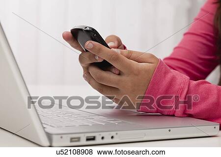 Stock Photo - USA, Illinois, Metamora, Woman texting on his mobile in office. Fotosearch