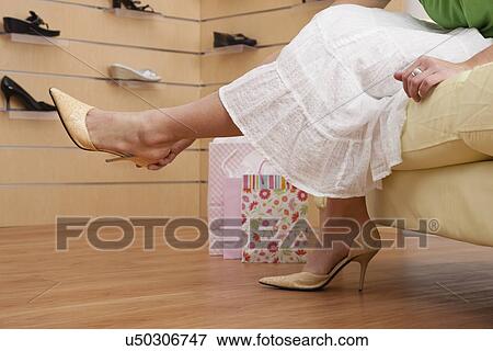 Stock Photo - USA, Illinois, Metamora, Woman trying on shoes in store, low section. Fotosearch