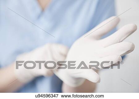 Stock Photo - USA, Illinois, Metamora, Woman wearing surgical gloves, close-up. Fotosearch