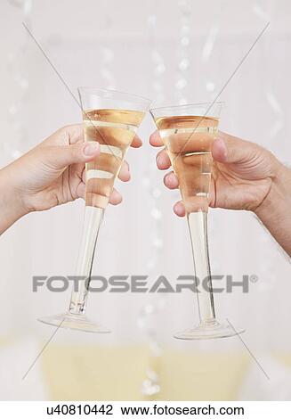Stock Image - USA, Illinois, Metamora, Womens hands toasting champagne. Fotosearch