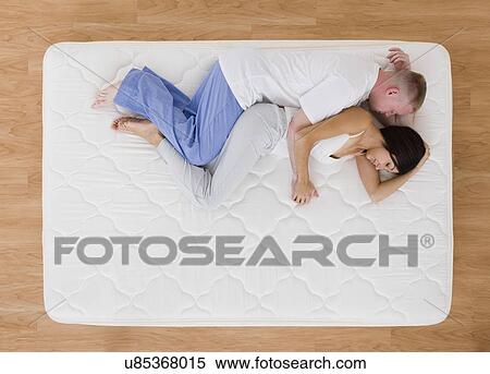 Stock Photography - USA, Illinois, Metamora, Young couple sleeping on mattress. Fotosearch