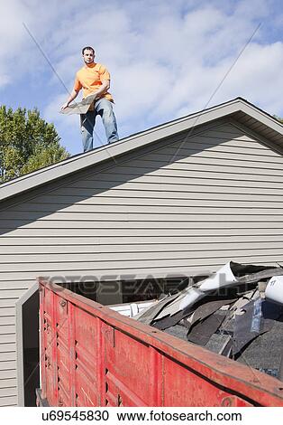 Stock Image - USA, Illinois, Metamora, Young man working on roof. Fotosearch