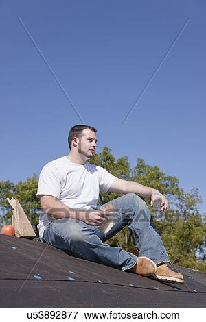 USA, Illinois, Metamora, Young man sitting on roof and eating lunch View Large Photo Image Stock Photo - USA, Illinois, Metamora, Young man sitting on roof and eating lunch. Fotosearch