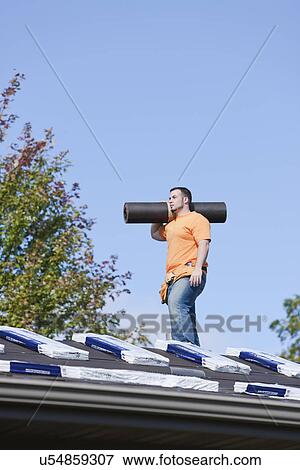 Stock Photo - USA, Illinois, Metamora, Young man working on roof. Fotosearch
