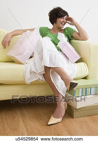 USA, Illinois, Metamora, Young woman with shopping bags sitting on sofa in shoes store and laughing View Large Photo Image Picture - USA, Illinois, Metamora, Young woman with shopping bags sitting on sofa in shoes store and laughing. Fotosearch