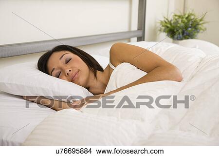 Picture - USA, Illinois, Metamora, Young woman asleep in bed. Fotosearch