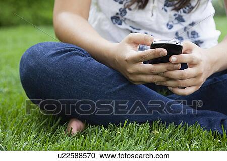 USA, Illinois, Metamora, Young woman texting on his mobile while sitting on grass View Large Photo Image Stock Image - USA, Illinois, Metamora, Young woman texting on his mobile while sitting on grass. Fotosearch