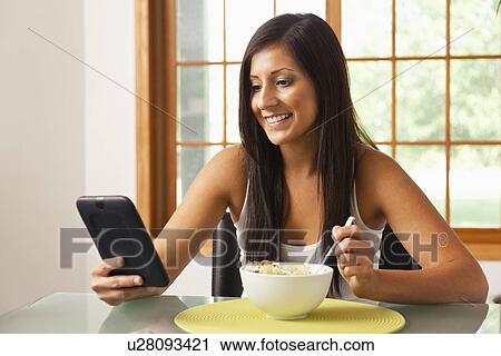 USA, Illinois, Metamora, young woman having Breakfast Cereal and holding digital tablet View Large Photo Image Stock Image - USA, Illinois, Metamora, young woman having Breakfast Cereal and holding digital tablet. Fotosearch