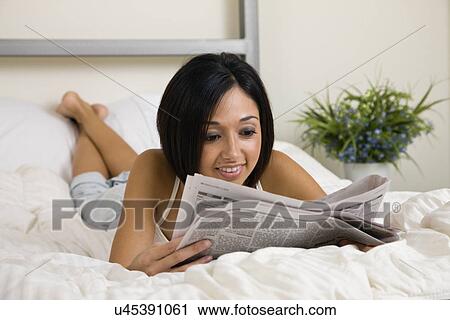 USA, Illinois, Metamora, Young woman lying in bed and reading newspaper View Large Photo Image Stock Image - USA, Illinois, Metamora, Young woman lying in bed and reading newspaper. Fotosearch