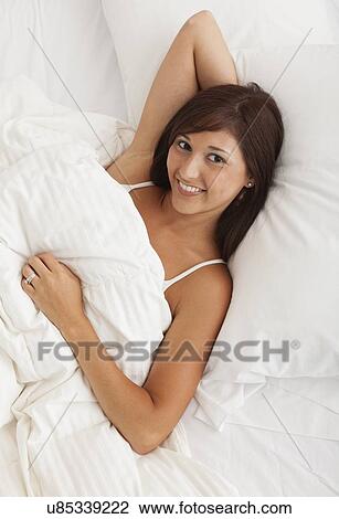 Stock Image - USA, Illinois, Metamora, young woman lying down in bed. Fotosearch