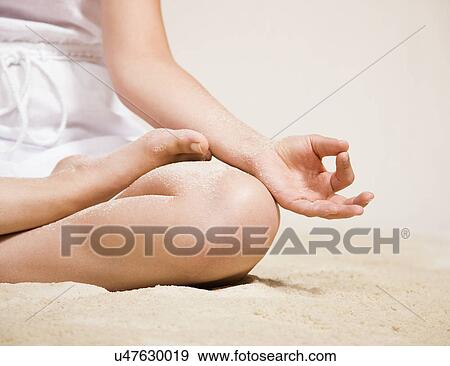 Stock Photo - USA, Illinois, Metamora, Young woman doing yoga on beach. Fotosearch
