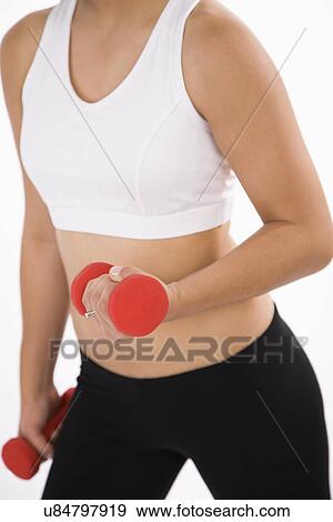 Stock Photo - USA, Illinois, Metamora, Young woman using dumbbells. Fotosearch