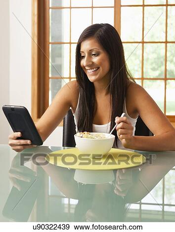 USA, Illinois, Metamora, young woman having Breakfast Cereal and holding digital tablet View Large Photo Image Stock Photo - USA, Illinois, Metamora, young woman having Breakfast Cereal and holding digital tablet. Fotosearch