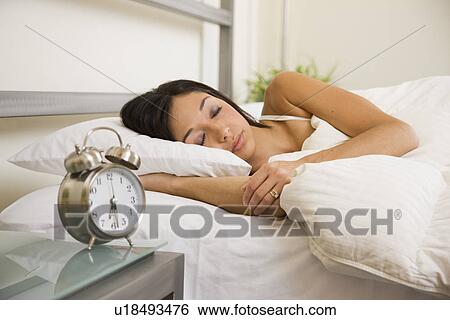Stock Photograph - USA, Illinois, Metamora, Young woman sleeping in bed. Fotosearch