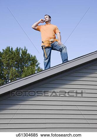 USA, Illinois, Metamora, Young worker standing on roof and talking via mobile phone View Large Photo Image Stock Photography - USA, Illinois, Metamora, Young worker standing on roof and talking via mobile phone. Fotosearch