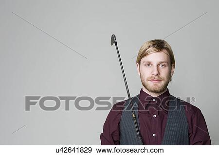 USA, Illinois, Peoria, Studio portrait of young man with golf club View Large Photo Image Stock Photo - USA, Illinois, Peoria, Studio portrait of young man with golf club. Fotosearch