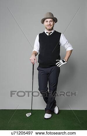 Stock Photo - USA, Illinois, Peoria, Studio portrait of young man with golf club. Fotosearch