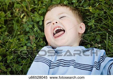 Stock Photography - USA, Illinois, Washington, Boy (2-3) lying on grass and laughing. Fotosearch
