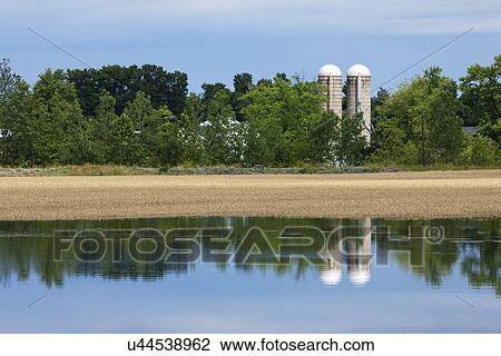 Stock Image - USA, Missouri, Field and silos in flood. Fotosearch