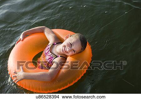 Picture - USA, Missouri, Stockton, Stockton Lake, girl (8-9) swimming in inflatable ring. Fotosearch