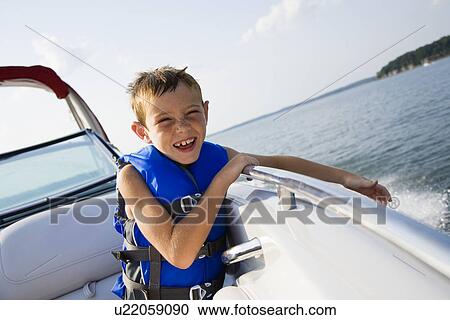 Stock Image - USA, Missouri, Stockton, Stockton Lake, boy (6-7) riding in boat. Fotosearch