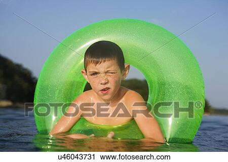 Stock Image - USA, Missouri, Stockton, Stockton Lake, boy (6-7) swimming in inflatable ring. Fotosearch