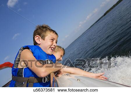 Stock Image - USA, Missouri, Stockton, Stockton Lake, boy (6-7) and girl (8-9) riding in boat. Fotosearch