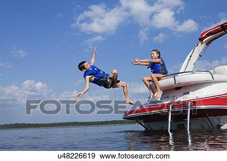 Stock Photo - USA, Missouri, Stockton, Stockton Lake, boy (6-7) and girl (8-9) playing on boat. Fotosearch