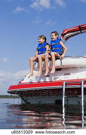 Stock Photo - USA, Missouri, Stockton, Stockton Lake, boy (6-7) and girl (8-9) sitting on boat. Fotosearch