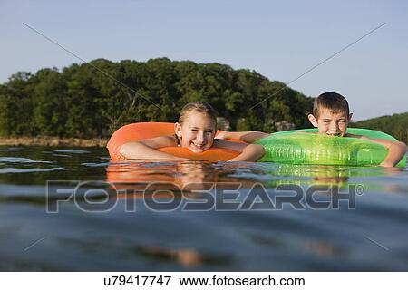 USA, Missouri, Stockton, Stockton Lake, boy (6-7) and girl (8-9) swimming in inflatable ring View Large Photo Image Stock Photo - USA, Missouri, Stockton, Stockton Lake, boy (6-7) and girl (8-9) swimming in inflatable ring. Fotosearch