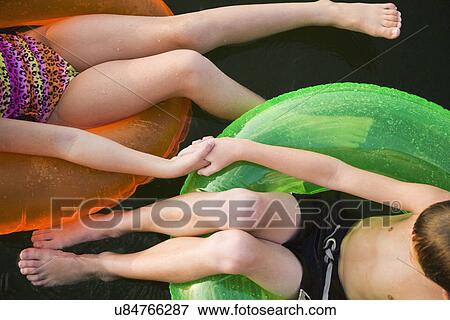 Stock Photo - USA, Missouri, Stockton, Stockton Lake, boy (6-7) and girl (8-9) swimming in inflatable rings. Fotosearch