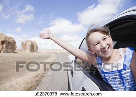 Stock Photo - USA, New Mexico, Girl (10-11) waving out of car window. Fotosearch