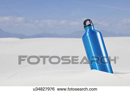 Stock Photograph - USA, New Mexico, Whitesands, Blue thermos buried in sand. Fotosearch