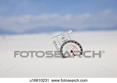 Stock Image - USA, New Mexico, Whitesands, Compass buried in sand. Fotosearch