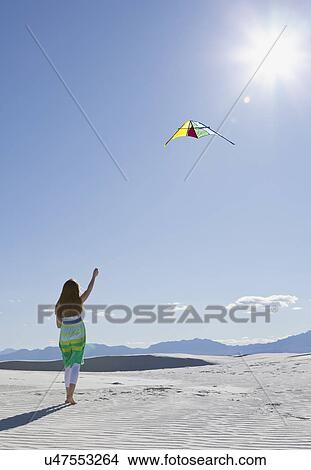 Picture - USA, New Mexico, Whitesands, Girl (10-11) flying kite on desert. Fotosearch
